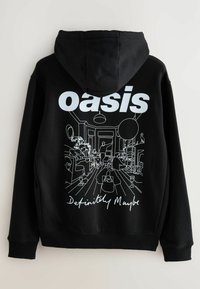 Zwarte hoodie met witte tekst "oasis" en een omtrekillustratie van een kamer op de rug. Het materiaal is een katoenmix met een gestructureerde afwerking.
