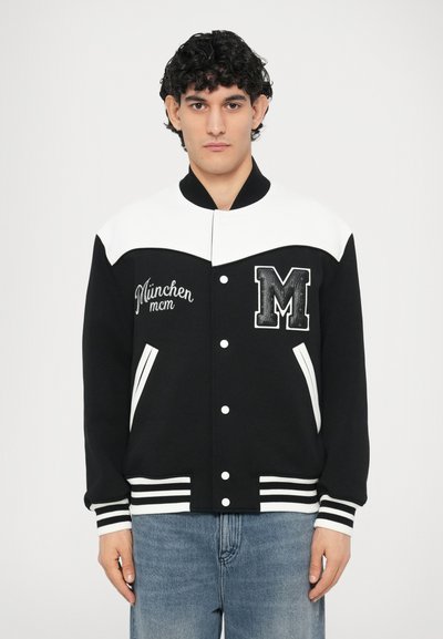 Schwarz-weiße Collegejacke mit rundem Kragen, "München" Stickerei, vorderen aufgesetzten Taschen sowie gerippten Bündchen und Saum.