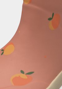 Ροζ ύφασμα με εκτυπώσεις πορτοκαλιών και πράσινα φύλλα, καμπυλωτό σχήμα με λευκή υφή στην άκρη.