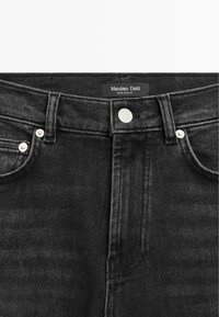 Ceinture de jean en denim noir avec bouton argenté et rivets, poches avant, passants pour ceinture, et étiquette « Massimo Dutti Made in Egypt ».