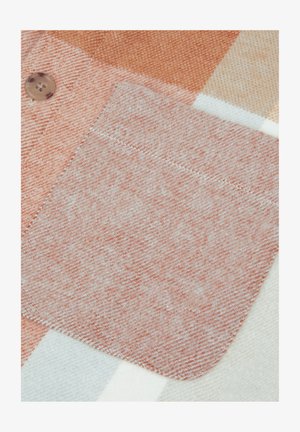 Terningsmønstret tekstil med en blød, ferskenfarvet lomme med en glat overflade. Knapdetalje i en lysebrun farve.