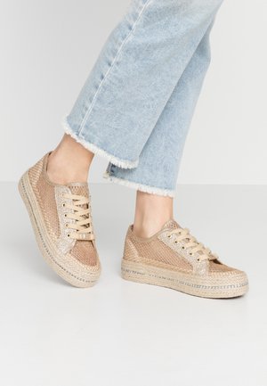 Sko med snørebånd, der har en vævet metallisk netoverdel og en flet-jute sål; har en flad, gummieret bund og en neutral beige farve.