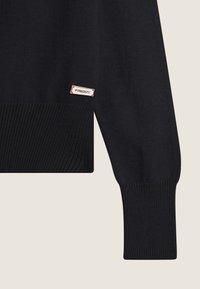 Schwarzer Strickpullover mit gerippten Bündchen, ausgestattet mit einem kleinen rechteckigen Logotag am Ärmel. Glatte Textur und taillierte Passform.