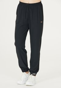 Schwarze Sporthosen mit einem elastischen Bund, Seiten Taschen und elastischen Bündchen. Mit einem kleinen goldenen Logo-Detail auf der Vorderseite.