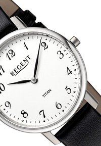 Montre en acier inoxydable argenté avec un cadran blanc, des chiffres arabes noirs et un bracelet en cuir noir. Présente des aiguilles des heures et des minutes noires.