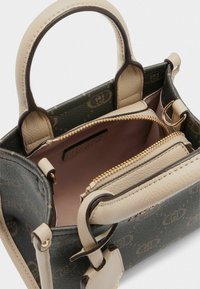 Kleine Handtasche mit einem beige und dunkelgrünen Außenbereich, ausgestattet mit einem Reißverschlussfach und zwei Griffen, innen mit hellrosa gefüttert.