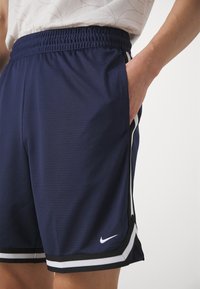 Pantalones cortos deportivos de color navy con un acabado texturizado, cinturilla elástica, bolsillos laterales y detalles en franjas blancas. Presenta el logo de Nike en el dobladillo.
