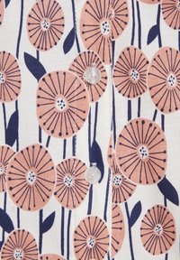 Floral button-up fabric featuring large peach flowers with dark blue stems and leaves on a white background; clear buttons add detail.
