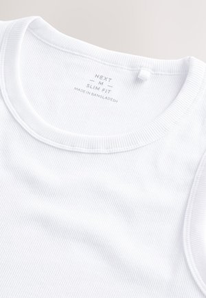 Débardeur blanc slim en tissu côtelé. Il présente un col rond, des détails cousus et une étiquette de marque située à l'intérieur du col.