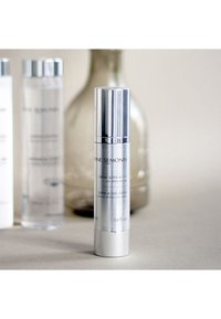 Silver pumpflaska med en slät yta, märkt "Crème Super Active," innehållande 1,6 fl. oz. kräm, placerad mot en neutral bakgrund.