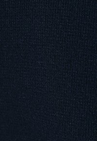 Tissu tricoté bleu foncé avec une fine texture côtelée, montrant un gros plan détaillé du motif textile.
