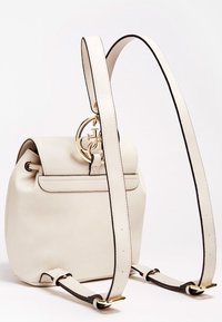 Sac à dos en cuir beige de forme arrondie, doté d'un rabat replié, de ferrures dorées et de bretelles ajustables avec des accents noirs.