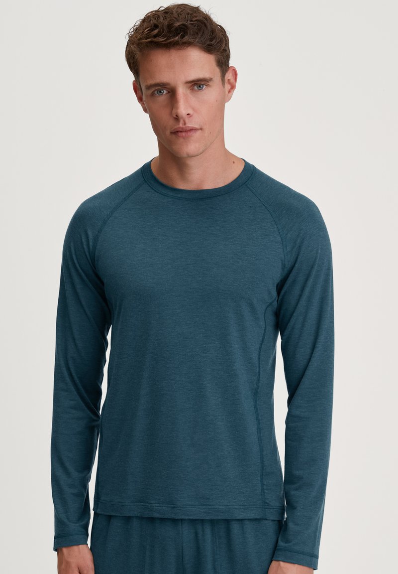 Teal lange mouw shirt met een ronde halslijn, gemaakt van textuurstof. Heeft raglanmouwen en een relaxte pasvorm. Eenvoudig ontwerp zonder patronen.
