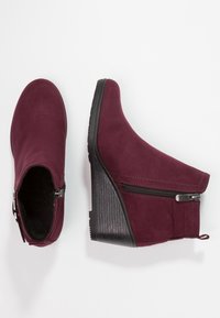 Burgunderfarbene Wedges mit Knöchelabsatz aus Wildleder, ausgestattet mit einem seitlichen Reißverschluss, einem strukturierten schwarzen Absatz und einer glatten Oberseite mit Nahtdetails.