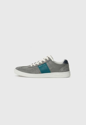 Grå mockask sneaker med en turkos läderaccentstrimma, vit gummisula och vita snören. Har en låg design och minimal varumärkesprofil.