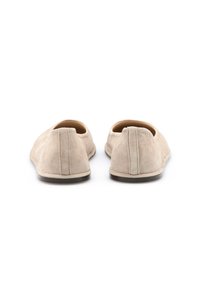 Beige Wildleder Slipper mit glatter Oberfläche und abgerundetem Zehenbereich, ausgestattet mit einer kontrastierenden dunklen Gummisohle und einer gesteppten Detailverarbeitung an der Ferse.