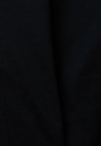 Tissu noir uni avec un pli vertical subtil au centre, montrant une texture fine et une réflexion minimale de la lumière.