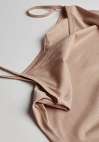 Světle růžové tílko s tenkými ramínky, hladkou texturou, zaobleným výstřihem a jemnými švy.