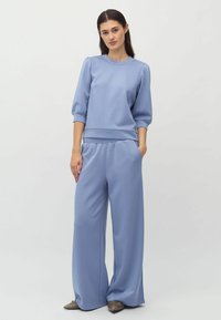 Pullover azzurro chiaro con maniche a tre quarti e pantaloni a gamba larga coordinati. Il tessuto ha una consistenza liscia e presenta una vita elastica.