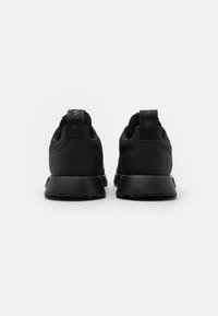 Black athletic shoes with a sleek design, featuring a smooth texture, rounded toe, and a reinforced heel with a loop for easy wear.