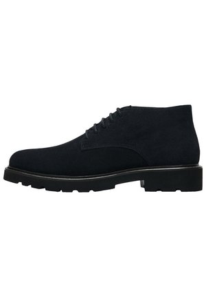 Bottines en daim noir avec un bout arrondi, des coutures subtiles, six œillets et une semelle en caoutchouc épaisse pour une bonne adhérence.