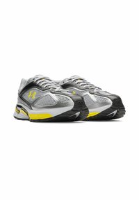 Gray and black athletic shoes with mesh upper, yellow accents, padded collar, and rubber sole featuring textured tread for stability.