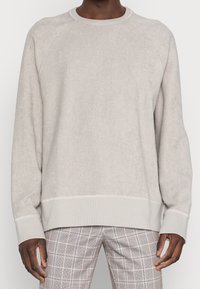 Light grey fleece sweatshirt with a round neckline, ribbed cuffs, raglan sleeves, and subtle texture, worn over checked pants.