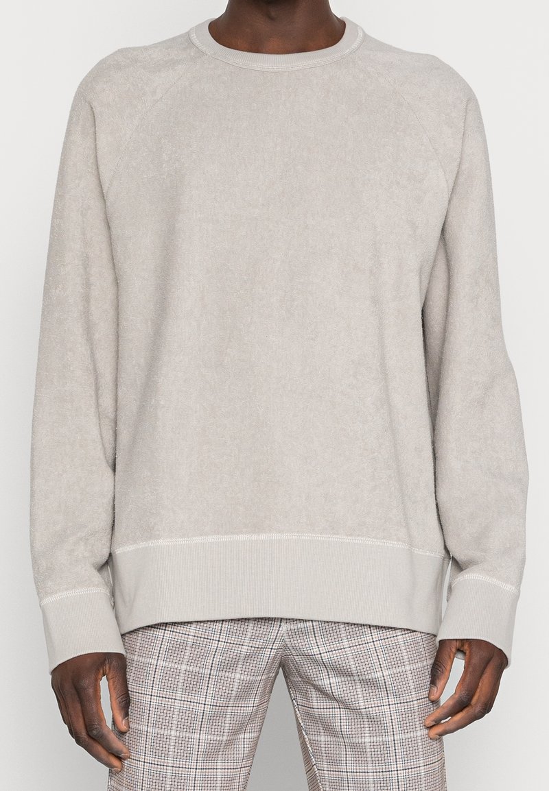 Light grey fleece sweatshirt with a round neckline, ribbed cuffs, raglan sleeves, and subtle texture, worn over checked pants.