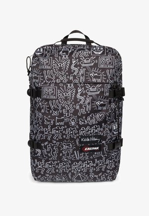 Mochila con un tejido negro y patrones abstractos en blanco. Incluye correas ajustables, un asa en la parte superior y una etiqueta de marca en la parte inferior.