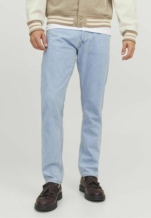 Jeans in denim azzurro chiaro con una vestibilità dritta, caratterizzati da un classico design a cinque tasche. Indossati con scarpe stringate marroni scure con dettagli frangianti.
