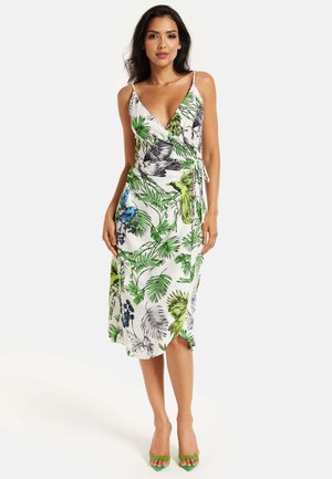 Wrap dress with a V-neck and adjustable tie, featuring a floral pattern in green and blue on white fabric. Paired with green heels.