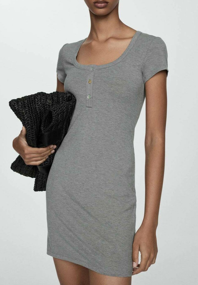 Abito grigio a coste con maniche corte, scollatura a girocollo e tre bottoni. La modella tiene una clutch nera con texture. Design semplice e aderente.