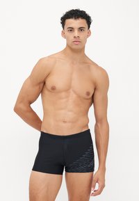Schwarze Badeshorts aus glattem Stoff mit einem kontrastierenden blauen geometrischen Muster an der Seite. Enganliegendes Design, bis zur Mitte des Oberschenkels.