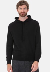 Schwarzer Kapuzenpullover mit Kordelzug. Verfügt über lange Raglanärmel und einen gerippten Saum. Hergestellt aus weichem, strukturiertem Stoff.