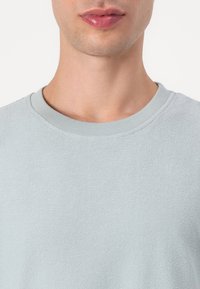 Light blue crewneck sweatshirt made from a textured material. Features a ribbed neckline and a casual fit without any patterns or accents.