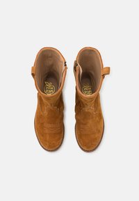 Stivaletti in suede marrone con cuciture decorative, chiusura con zip e linguetta per facilitarne l'indossamento; interno foderato con logo del brand sulla soletta.