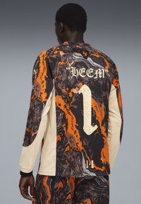 Langærmet trøje med et levende orange og sort marmor design, cremefarvede meshsleeves og nummeret "1" med navnet "HEEM" på ryggen.