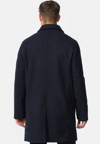 Marineblå uldblandingsfrakke med et struktureret design, lange ærmer, bred krave, lige skæring og sidelommer. Glat tekstur med minimale accenter.