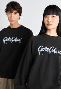 Zwarte sweatshirts met een druppelend blauw textontwerp. Bevat een ribgebreide halslijn en manchetten, met klassieke raglanmouwen.