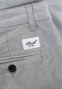Gray corduroy pants featuring a textured surface, a back pocket with a black button, and a white label with black text reading "Reell est. 1997."