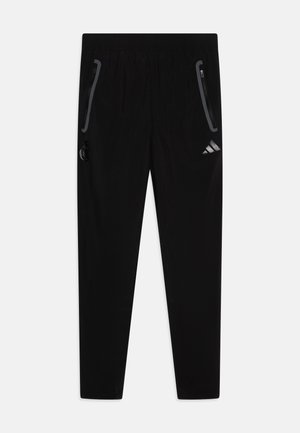 Zwarte sportieve broeken met een elastische tailleband, twee zijzakken met ritssluiting en een klein logo op het lagere rechterbeen. Gladde textuur, taps toelopende pasvorm.