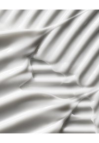 Surface en céramique blanche avec une finition brillante, présentant des motifs ondulés et des textures lisses. La lumière se reflète sur son design ondulant.