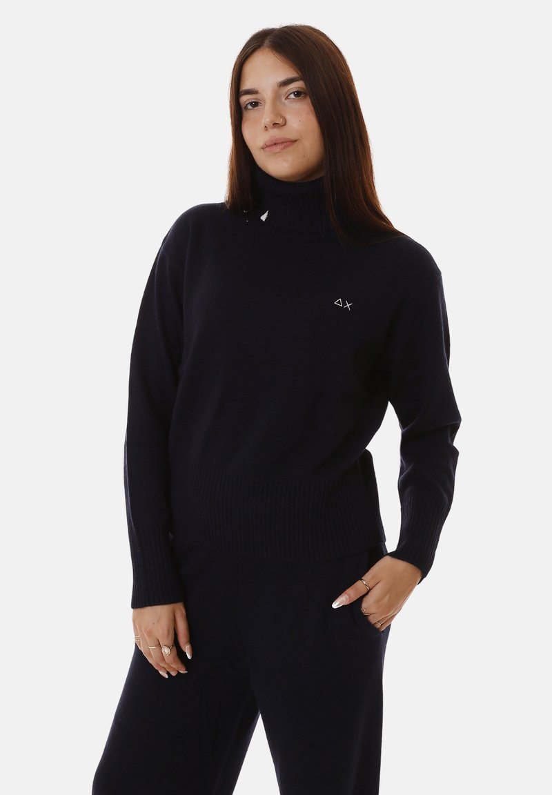 Maglione a collo alto in un blu scuro con texture a coste, maniche lunghe e piccolo logo sul petto. Tessuto morbido, vestibilità casual.