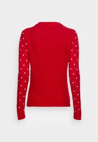 Pull rouge à manches longues avec des pois blancs sur les manches, dos uni, et bordures côtelées au niveau de l'ourlet et des poignets.