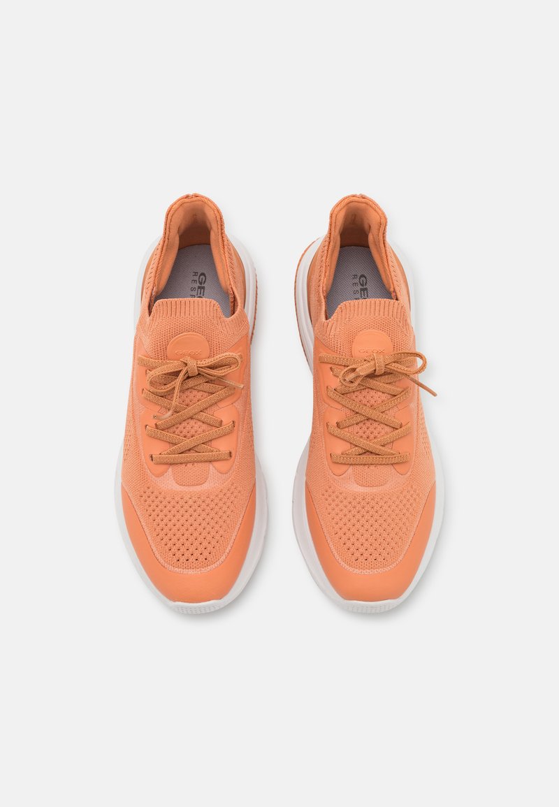 Sneakers arancioni in rete con parte superiore testurizzata, punta tonda e suola bianca flessibile. Presentano lacci coordinati e logo sul lato.