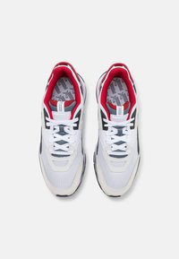 Scarpe da ginnastica bianche con accenti in rete e camoscio, fodera interna rossa, dettagli neri e lacci bianchi; presentano una soletta grigia con motivo.