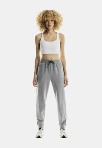 Pantaloni de trening gri cu talie elastică și șnur, asortați cu un top scurt alb. Ținuta are un fit casual și o textură netedă.