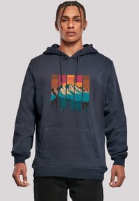 Navy blue hoodie with a front pocket, featuring a colorful mountain and forest graphic in rectangular panels. Soft fabric, relaxed fit.