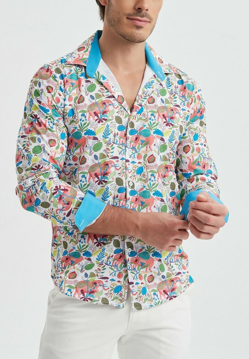 Chemise à manches longues avec un imprimé coloré floral et animal sur fond blanc, dotée d'un col bleu et d'accents aux poignets.