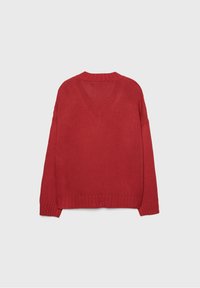Rode gebreide trui met een losse pasvorm, geribbelde halslijn en zoom. Heeft aangesneden schouders en een textuurstof voor comfort. Geen patronen of accenten.